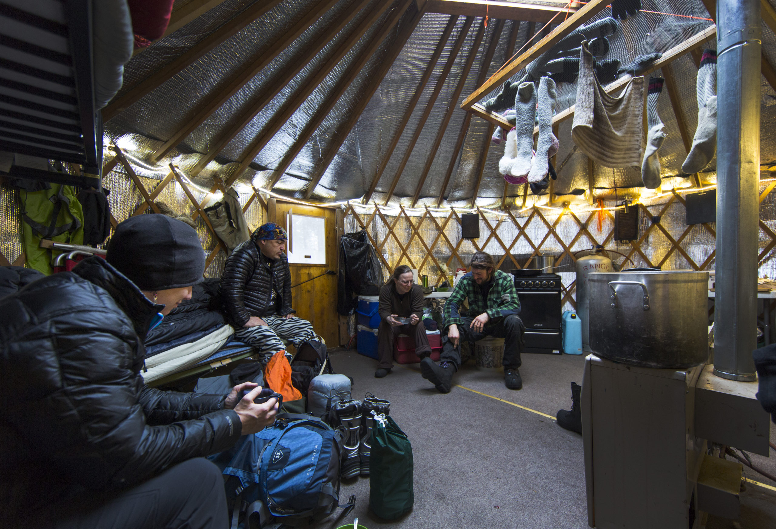 White Wilderness Riders resting in a yurt with gear and clothes drying