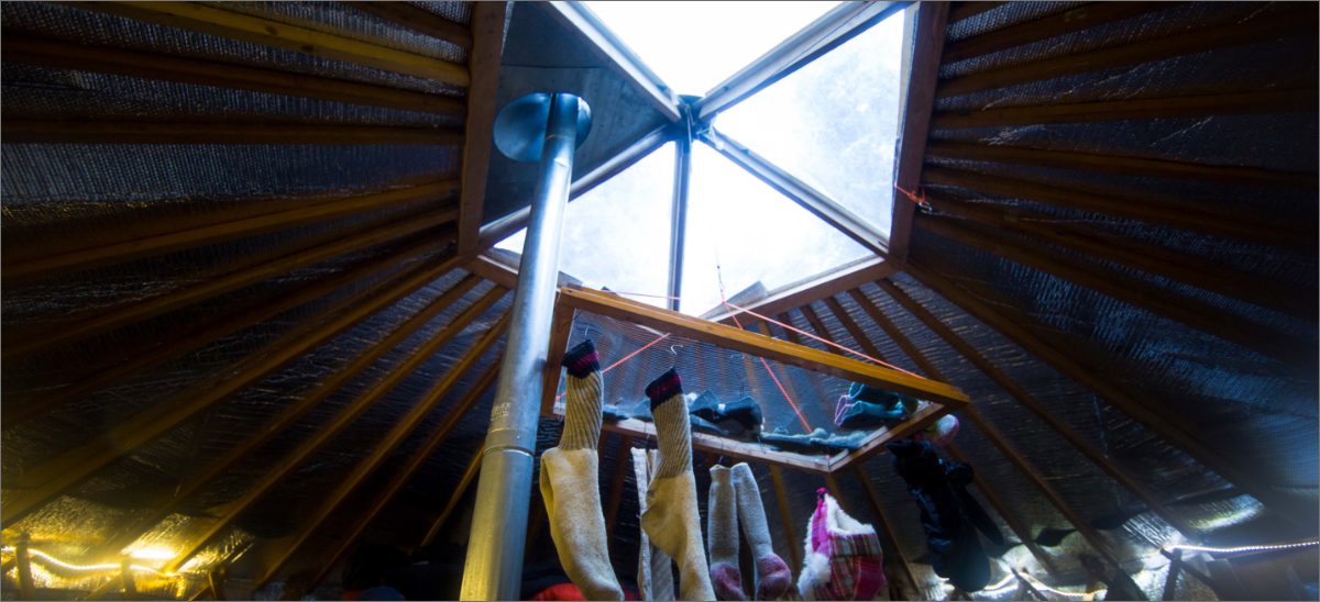 Looking at the top of a yurt from the inside.  Socks are hanging from a skylight to dry.