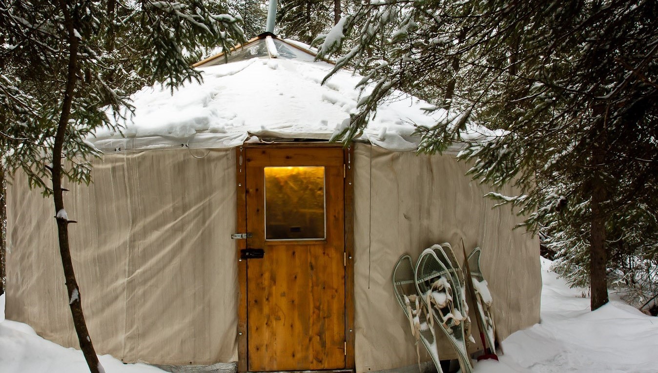 A snow covered yurt in the wilderness.